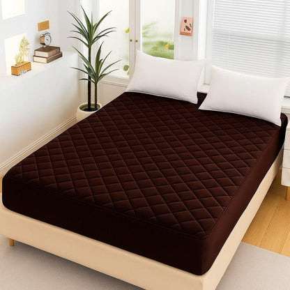 Chocolate Brown Quilted Waterproof Mattress Fitted Bed Sheet on modern beige bed with white pillows and indoor plant.