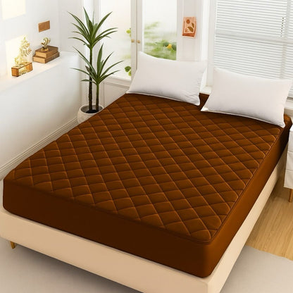 Chocolate Brown Quilted Waterproof Mattress Fitted Bed Sheet on modern beige bed with white pillows and indoor plant.