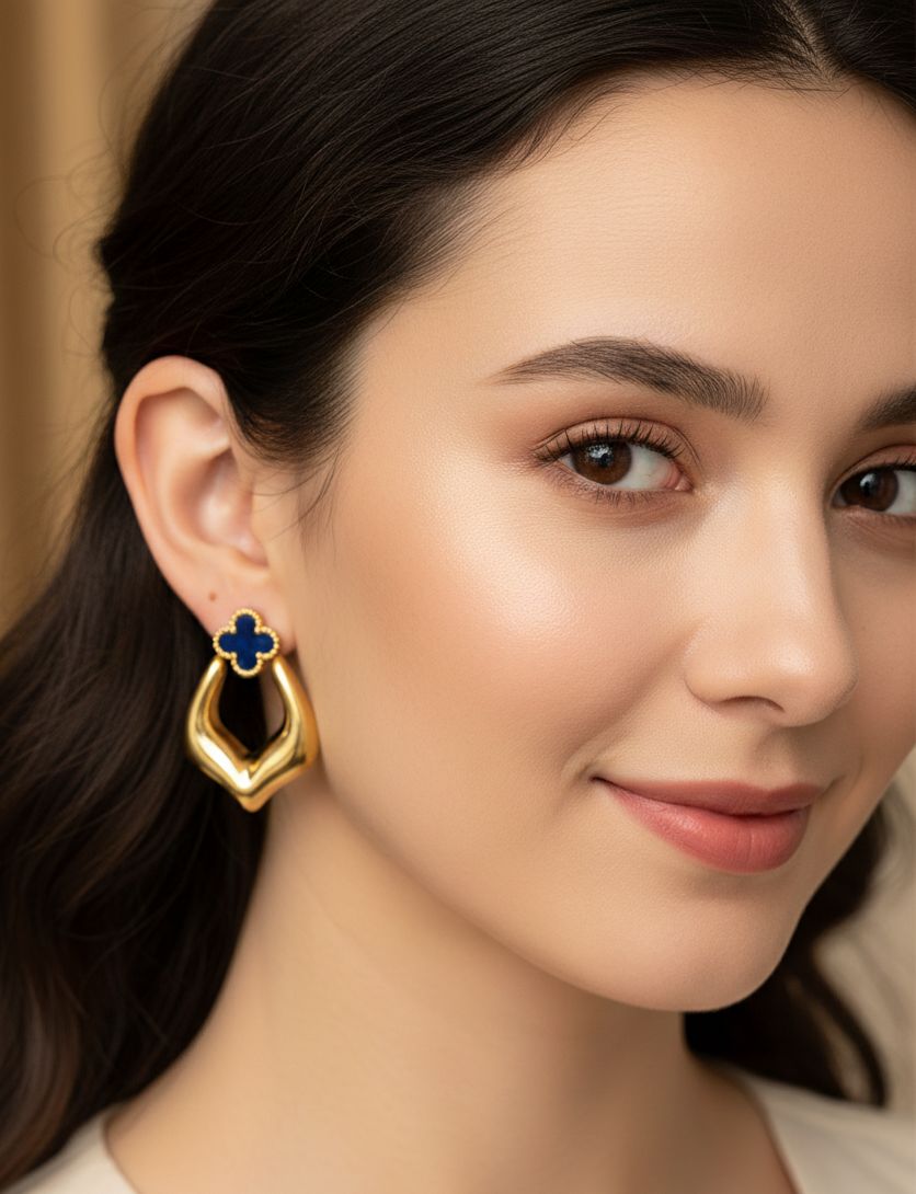 Close-up of a woman wearing a gold earring with a blue gemstone.