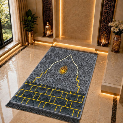 A rectangular prayer rug with a gray and blue Islamic pattern, featuring a central white arch, a gold lantern motif, and yellow grid lines, displayed on a polished marble floor in a luxurious interior setting.