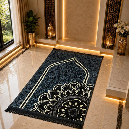 A rectangular prayer rug with a dark navy blue background, cream arch motif, and large cream mandala design near the bottom, shown on a polished beige marble floor in a decorated interior.