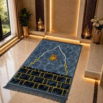 A blue patterned prayer rug with gold and white details, displayed on a polished marble floor in a luxurious, warmly lit interior setting.