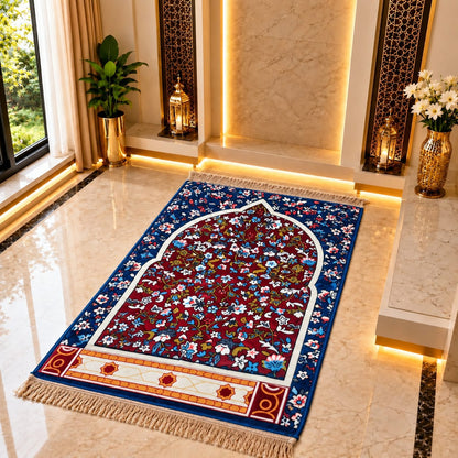 A rectangular prayer rug with a floral arch design is displayed on a polished marble floor in a luxurious, warmly lit room with plants and decorative lanterns.