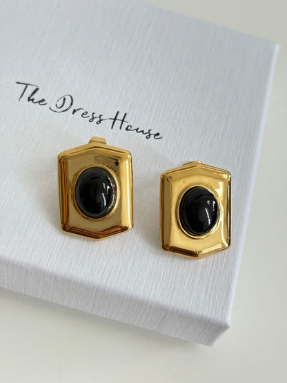 Pair of gold earrings with black centers on a white card with 'The Dress House' branding.