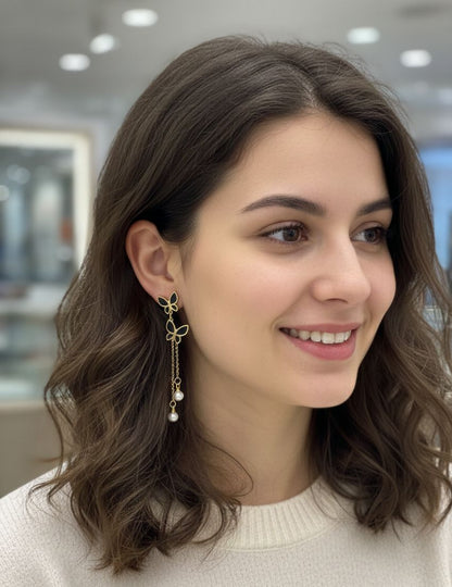 Woman wearing a gold earring with a pearl, smiling indoors.